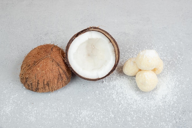 Sliced coconut with round sweet cookies on white surface.