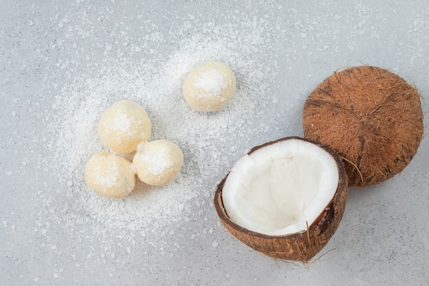 Sliced coconut with round sweet cookies on white surface