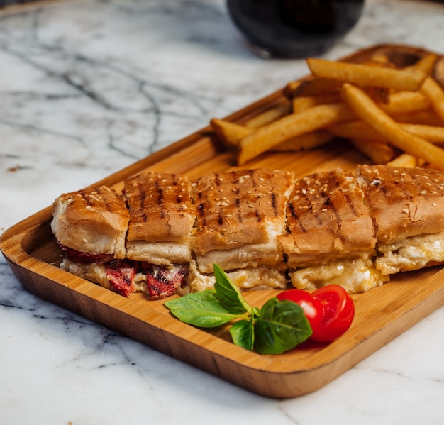 Sliced doner with french fries and vegetables on wooden board