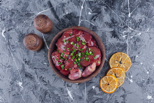 Sliced dried lemons and offal in a bowl on the blue surface