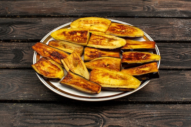 Sliced eggplants fried tasty on a round plate and rustic wooden desk