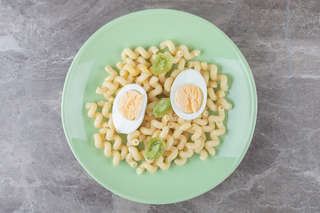 Sliced eggs and macaroni on green plate.
