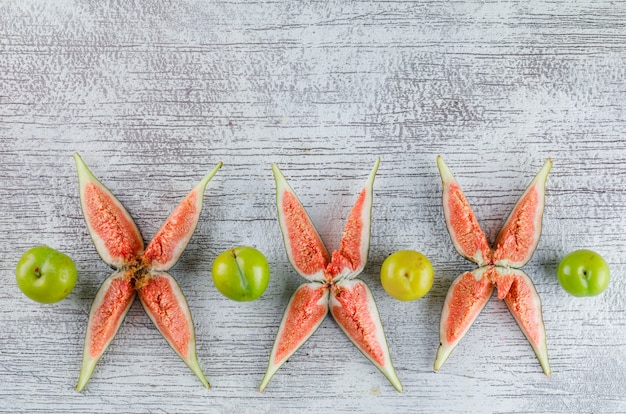 Free photo sliced figs with green plums on grungy,