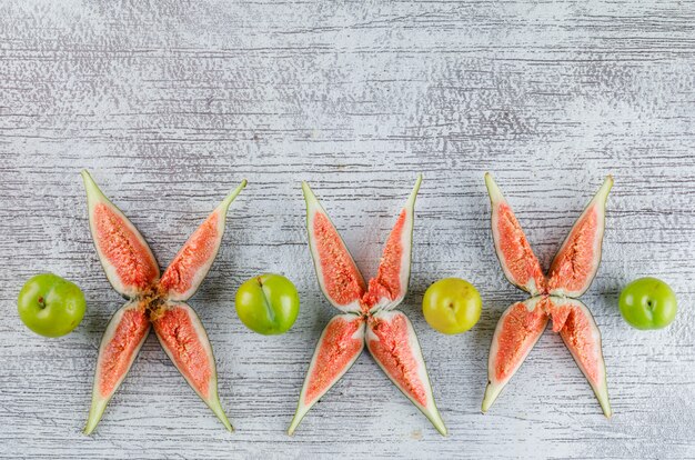 Sliced figs with green plums on grungy,