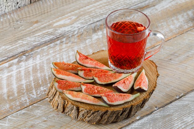 Sliced figs with herbal tea on a wooden board on wooden, high angle view.