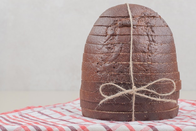 Sliced fresh brown bread in rope on tablecloth