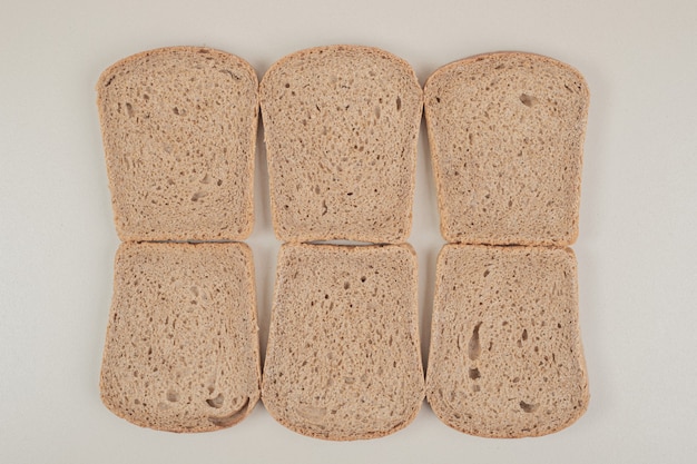 Free photo sliced fresh brown bread on white surface