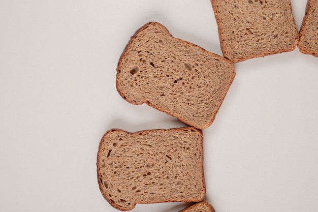 Foto gratuita pane integrale fresco affettato sulla superficie bianca