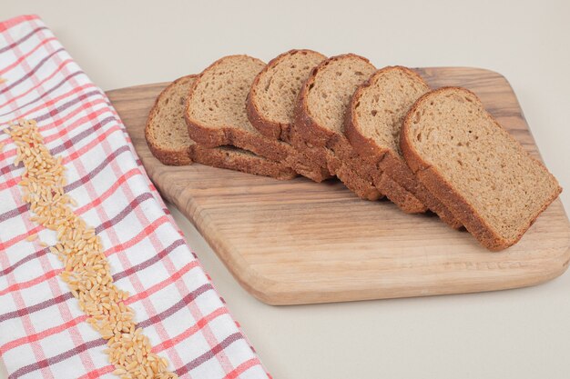 Sliced fresh brown bread on wooden board