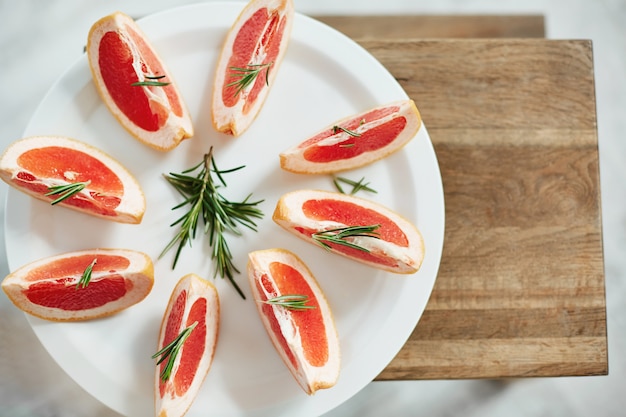 하얀 접시에 신선한 자 몽과 로즈마리를 슬라이스. 위에서. 건강 피트니스 다이어트 식품