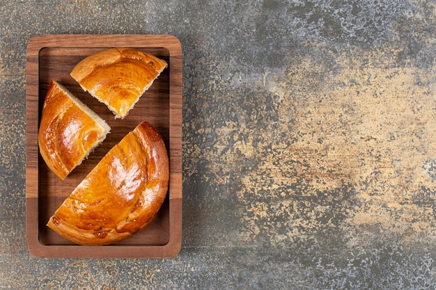 Sliced fresh pastry on wooden plate.