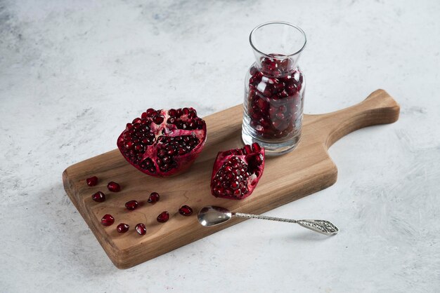 Sliced fresh pomegranate with a jug on wooden board. 