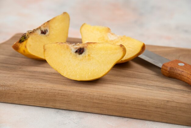 얇게 썬 신선한 모과 과일과 칼을 나무 판자에 올려 놓으세요.