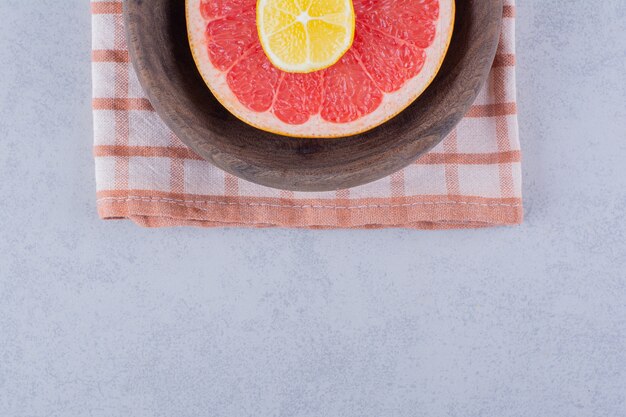 Free photo sliced fresh ripe grapefruit and lemon in wooden bowl.