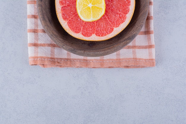 Sliced fresh ripe grapefruit and lemon in wooden bowl.