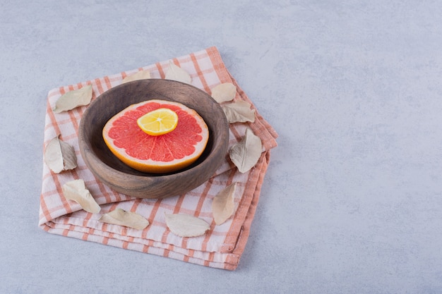 Нарезанный свежий спелый грейпфрут и лимон в деревянной миске.
