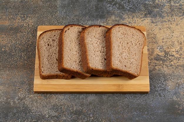Sliced fresh rye bread on wooden board.
