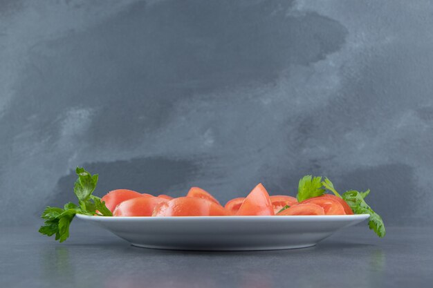 하얀 접시에 신선한 토마토와 파슬리를 얇게 썬다.
