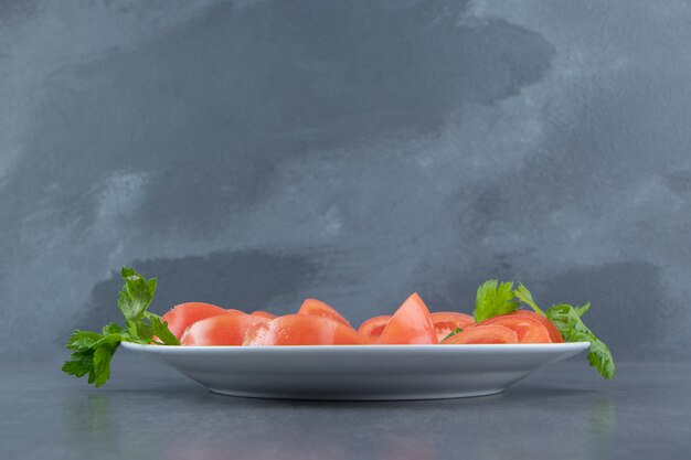 Sliced fresh tomatoes and parsley on white plate. 