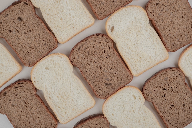 Pane bianco e marrone fresco affettato sulla superficie bianca