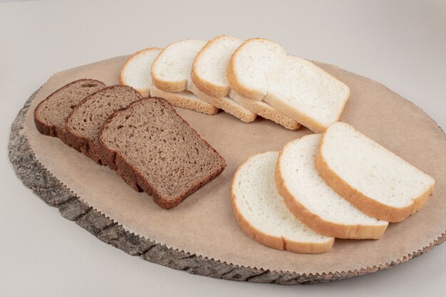 Sliced fresh white and brown bread on wooden plate . High quality photo