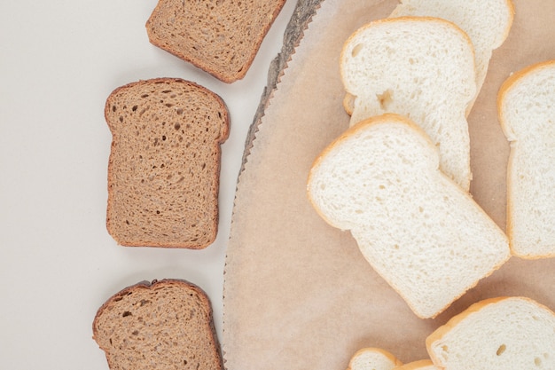 Sliced fresh white and brown bread on wooden plate 