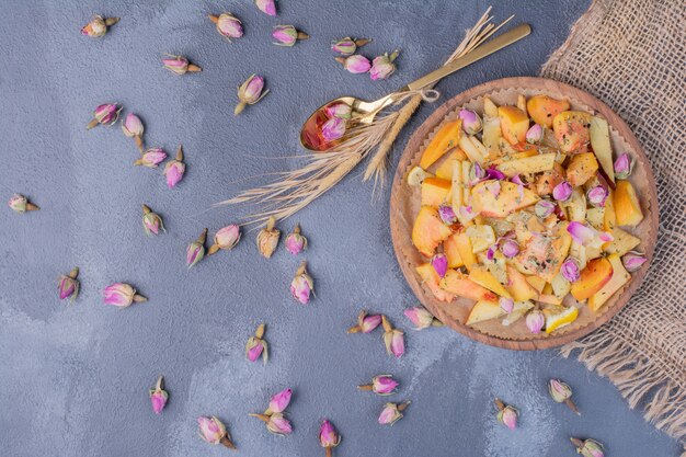 Sliced fruit plate with flowers on blue.