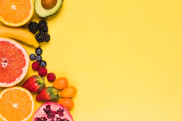 Нарезанные фрукты и ягоды на желтом фоне
