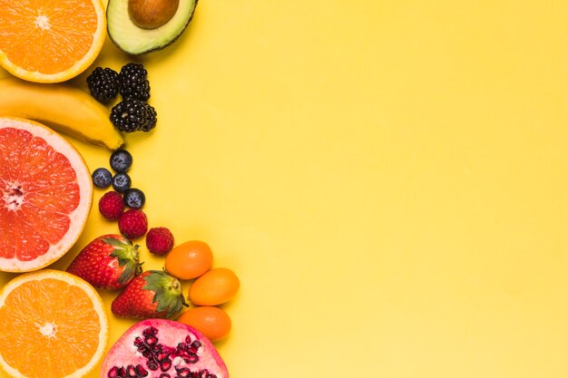 Sliced fruits and berries on yellow background 