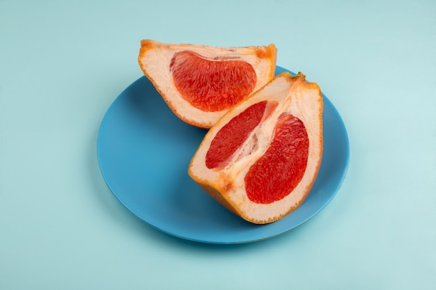 Sliced grapefruit juicy mellow inside blue plate on a ice-blue