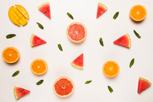 Sliced grapefruit watermelon orange mango and green leaves