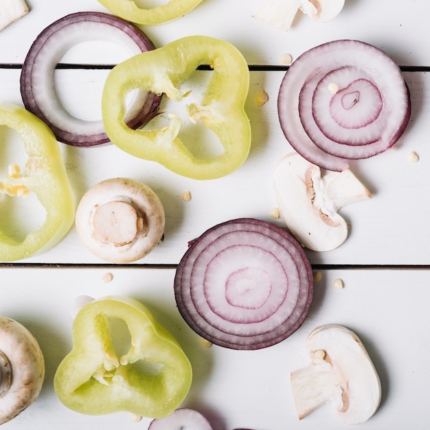 Sliced green bell pepper; mushrooms and onions on wooden backdrop