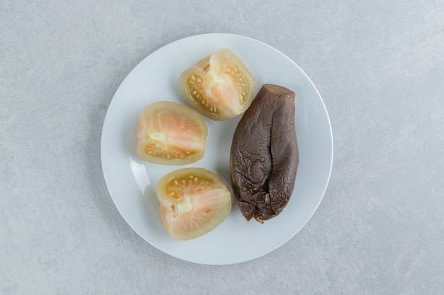 Sliced green tomatoes and eggplant on white plate.  