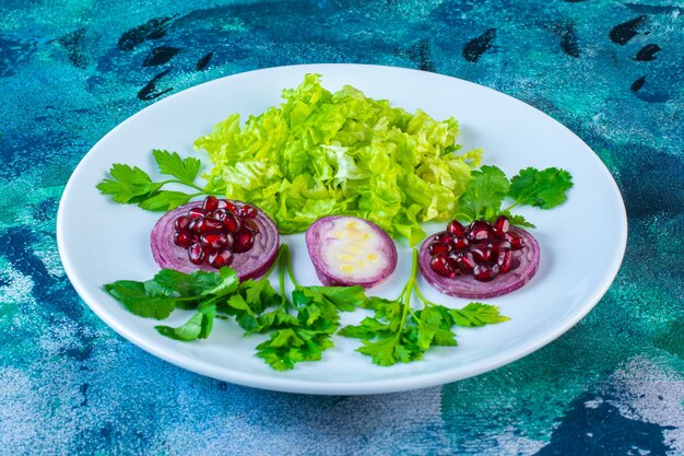 Sliced greenery vegetables and pomegranate arils on a plate 