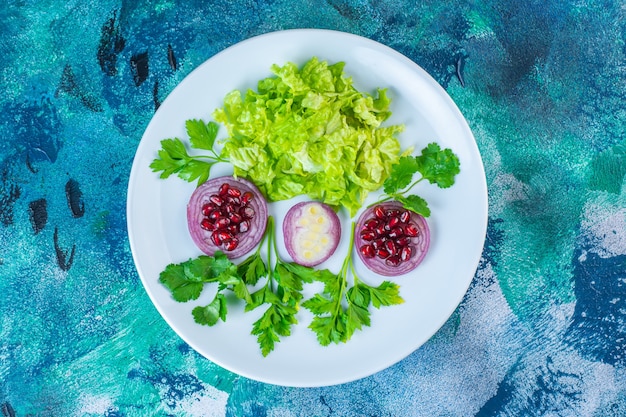 スライスした緑の野菜とザクロの仮種皮を皿に盛り付けます