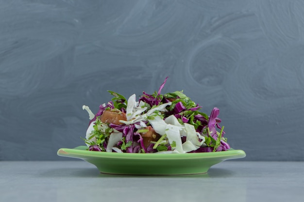 Sliced greens, and red cabbage on a plate , on the marble background.