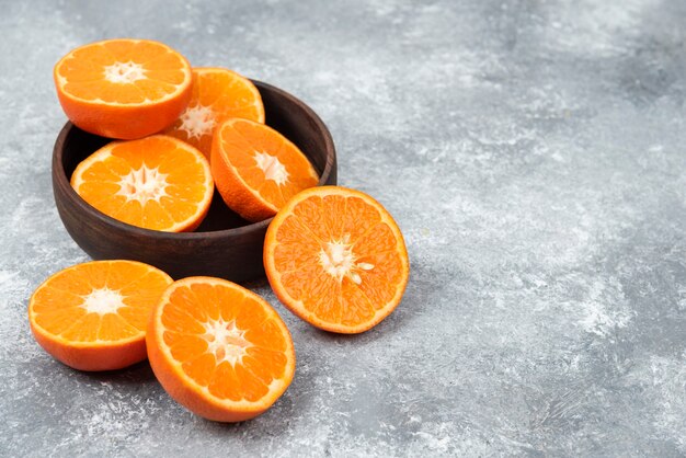 Sliced juicy fresh orange fruits in a wooden bowl .