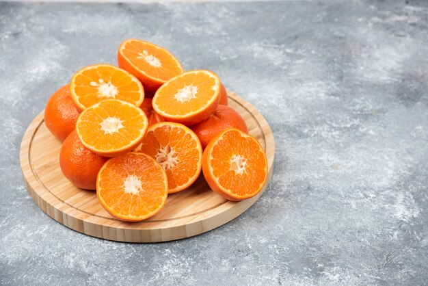 Sliced juicy fresh orange fruits in a wooden plate .