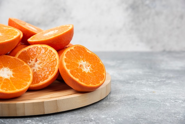 Foto gratuita frutta arancione fresca succosa affettata in un piatto di legno.