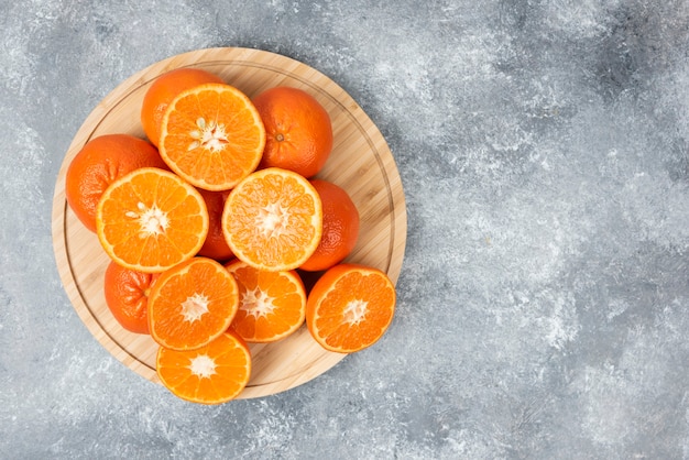 Sliced juicy fresh orange fruits in a wooden plate .