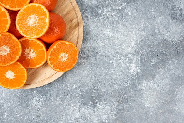 Sliced juicy fresh orange fruits in a wooden plate .