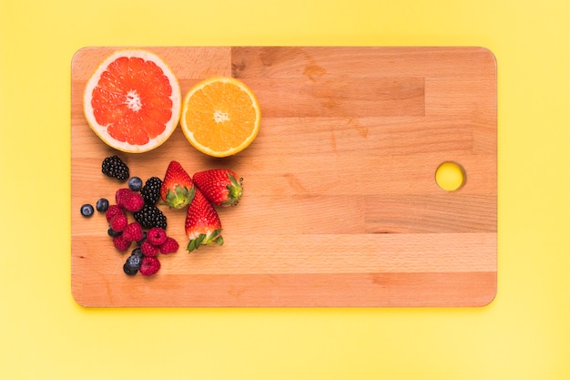 Sliced juicy orange lemon strawberry blackberry raspberry and currant on cutting board 