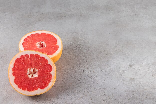 Sliced juicy ripe grapefruit placed on stone table.