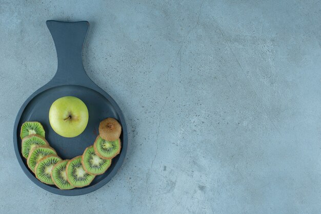 Sliced kiwi and apple in a pan , on the marble background. High quality photo