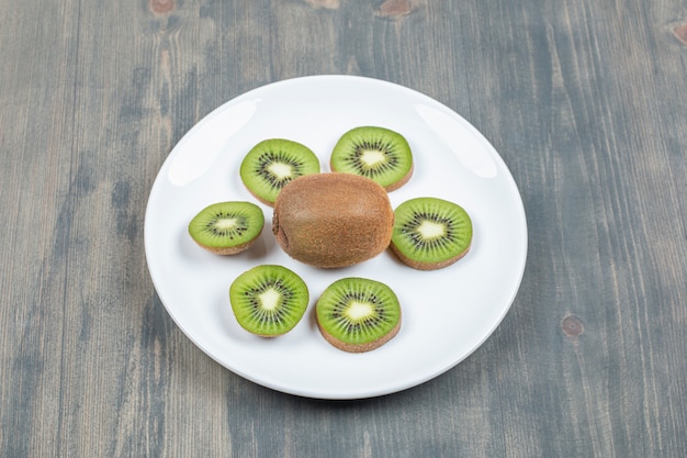 Foto gratuita kiwi a fette isolato su un piatto bianco