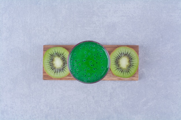 Free photo sliced kiwi and kiwi juice on a board on marble table.