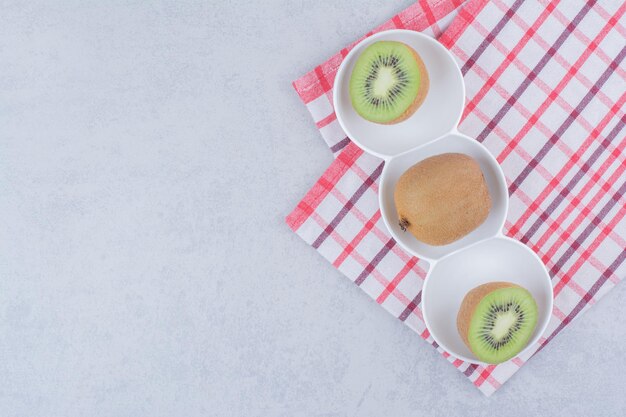 A sliced kiwi in white plate on tablecloth. High quality photo