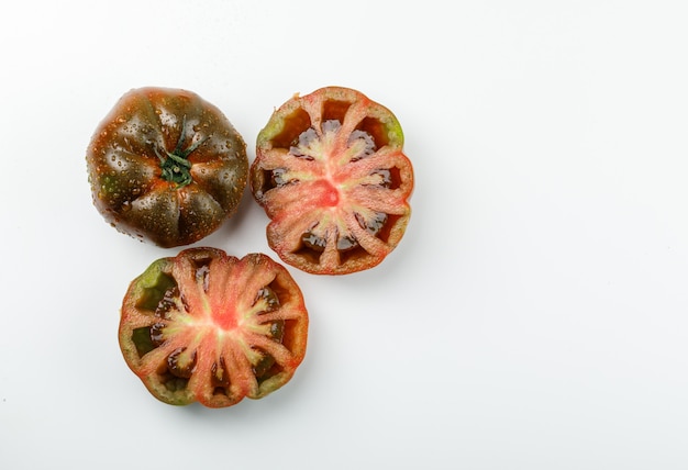 흰 벽에 kumato 토마토를 슬라이스. 평평하다.