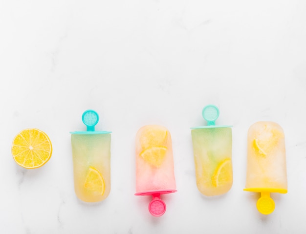 Free photo sliced lemon and fresh ice popsicle with citrus on colorful sticks