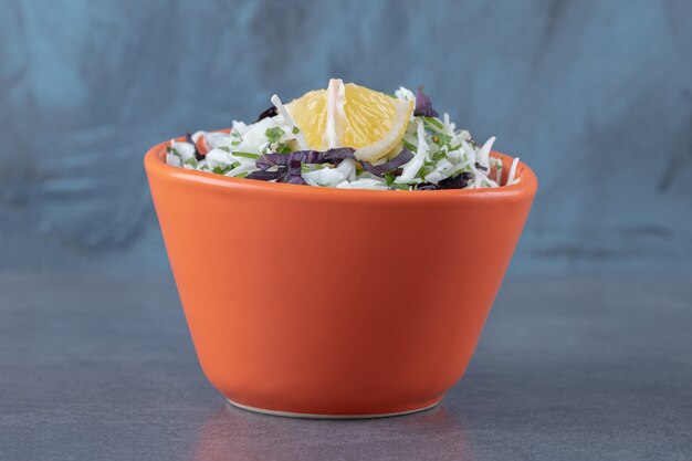 Sliced lemon with grated vegetables, on the marble surface.